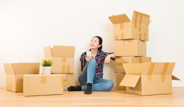 Woman preparing to move house surounded by moving boxes