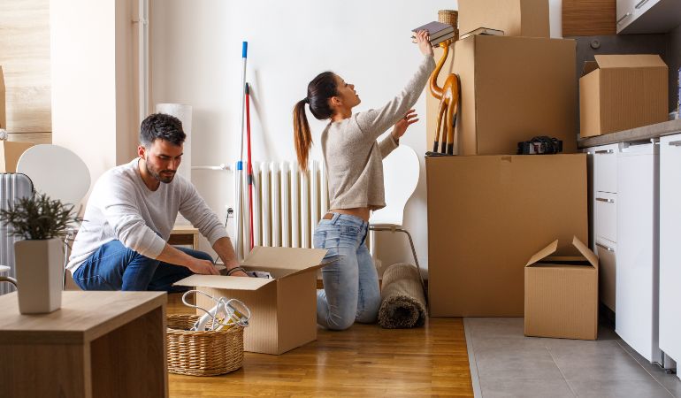 Couple packing moving boxes to move in together