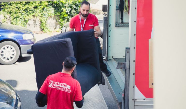 Team of expert movers carying a sofa correctly