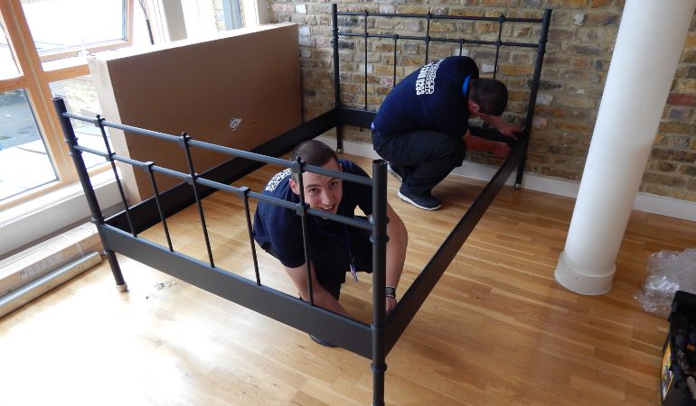 Professional movers dismantling a bed for a move