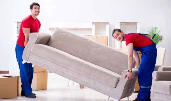 Removals specialists taking a sofa into storage