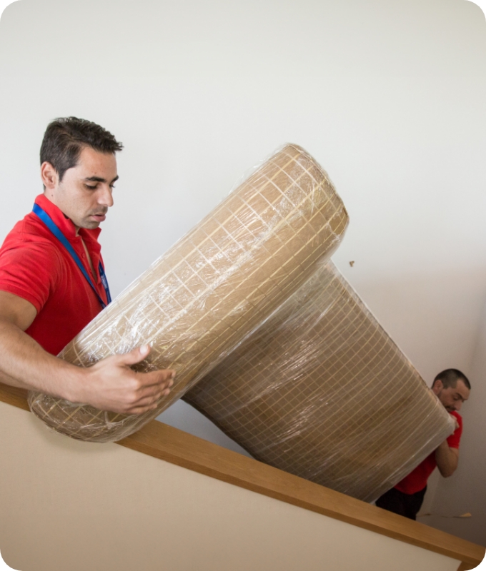 The image shows two movers who are carrying a couch down the stairs of a house during a service.