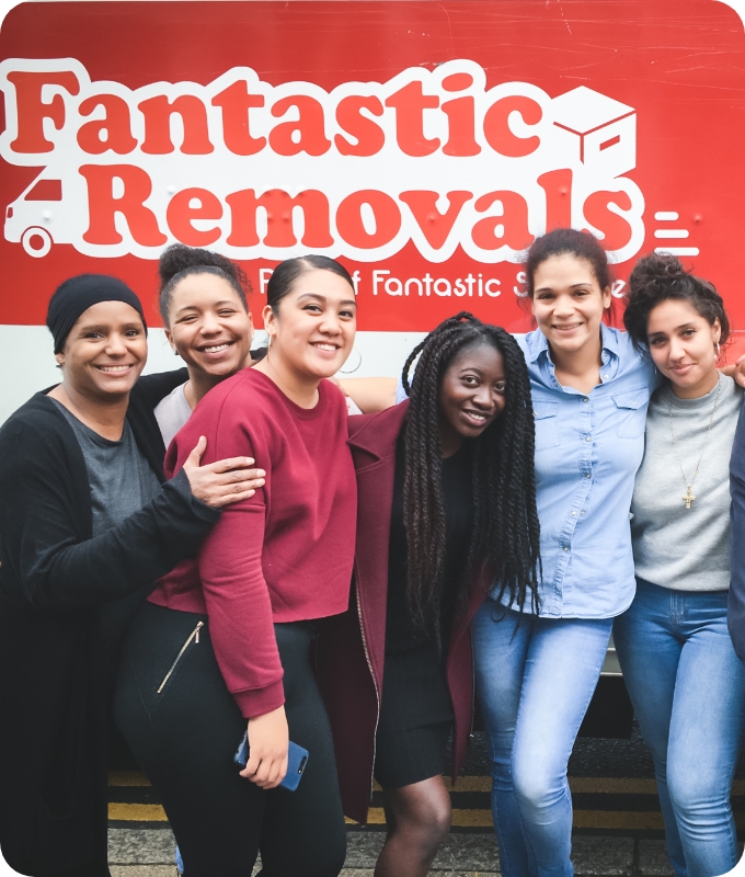 The image shows a group of students who are standing in front of a Fantastic Removals logo taking a group photo after a service.